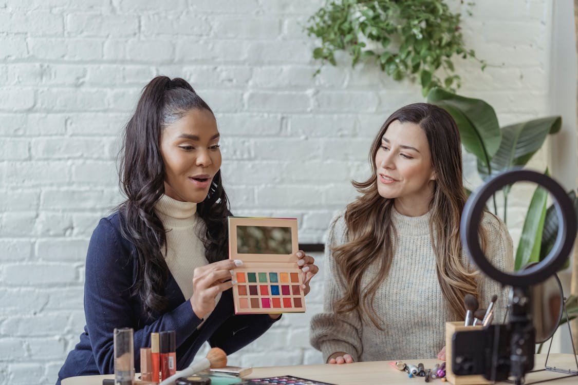 Influencer marketing Free Young diverse ladies recording vlog about makeup products on smartphone Stock Photo