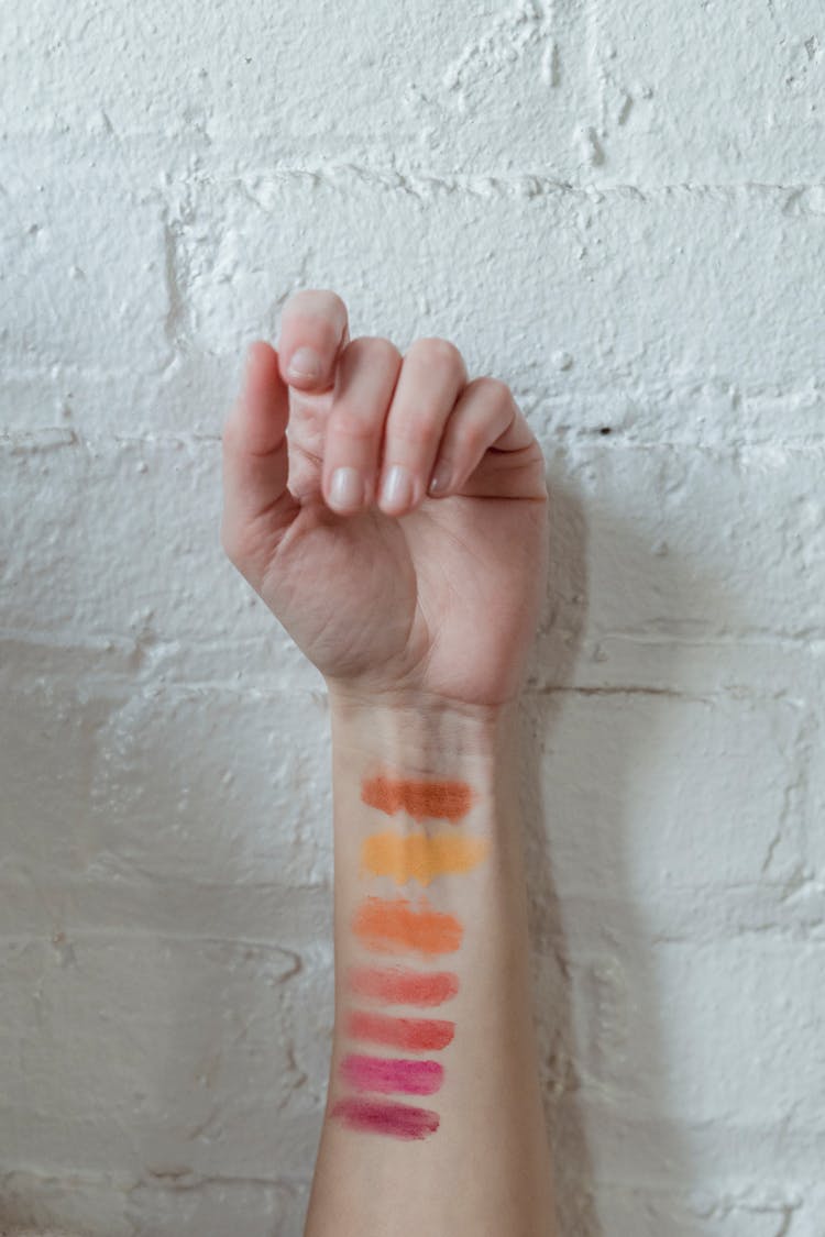 Crop Unrecognizable Woman Holding Hand Near Brick Wall After Testing Of Makeup Products