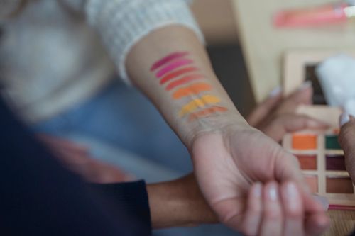 Free Crop anonymous female makeup artists testing new palette of colorful eyeshadows on arm in modern beauty salon Stock Photo