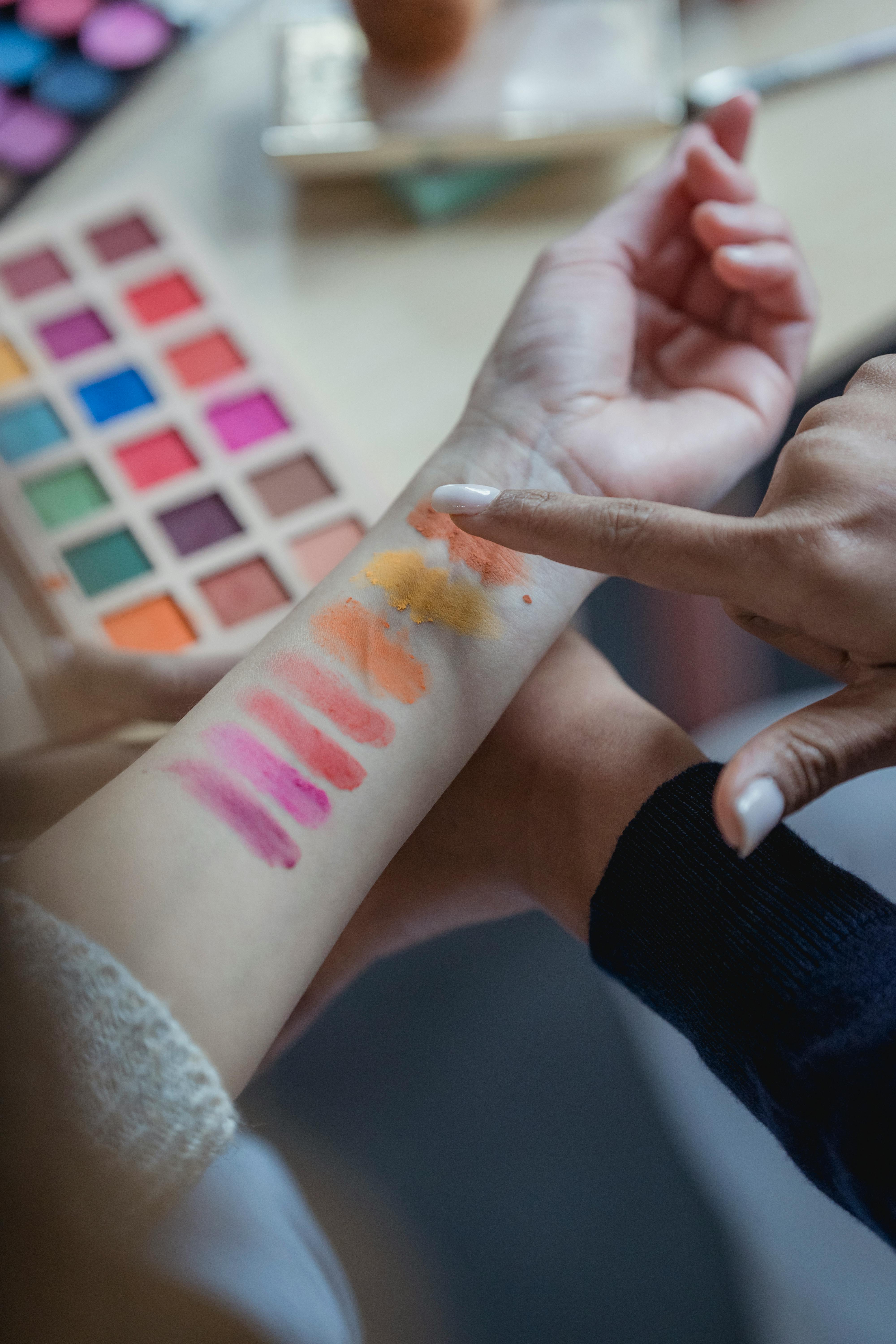 unrecognizable ladies testing new palette of colorful eyeshadows