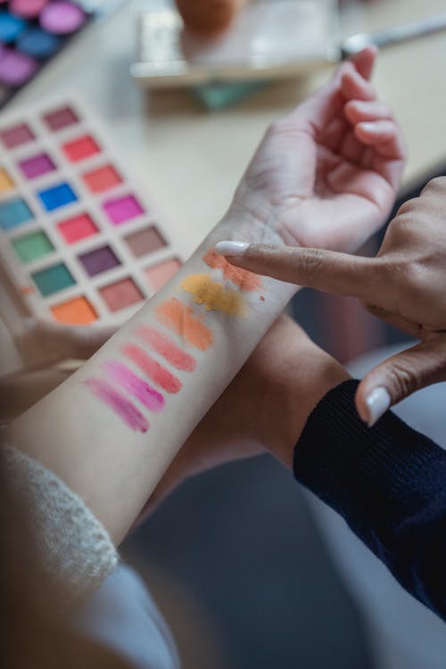 Unrecognizable ladies testing new palette of colorful eyeshadows