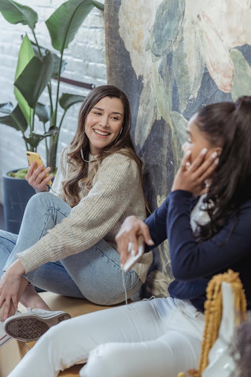 Free Cheerful young multiracial girlfriends listening to songs in earphones at home Stock Photo