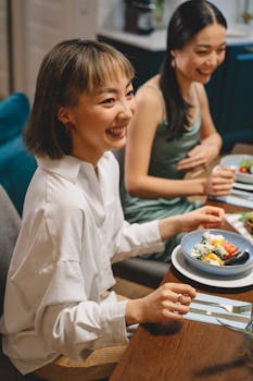 Two women enjoying a delightful dinner together, smiling and sharing a moment indoors.