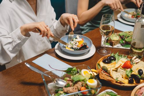 Free Elegant dining setting featuring fresh salad, dishes, and white wine, capturing a social gathering ambiance. Stock Photo