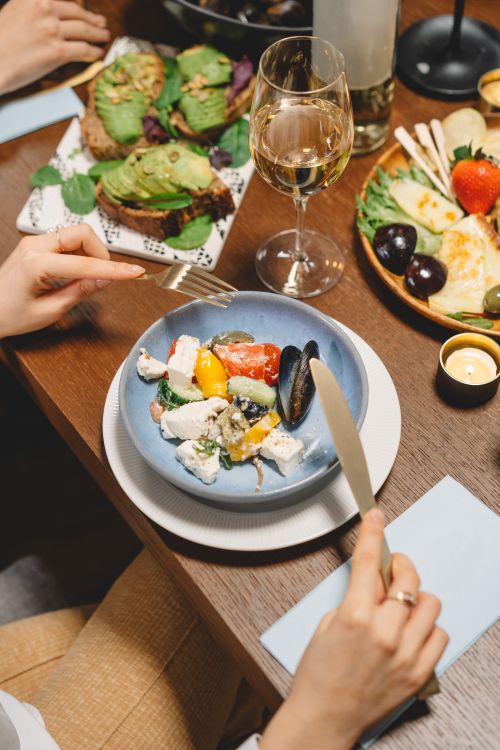 Free Elegant dinner setting featuring a fresh salad, mussels, and wine with ambient mood lighting. Stock Photo
