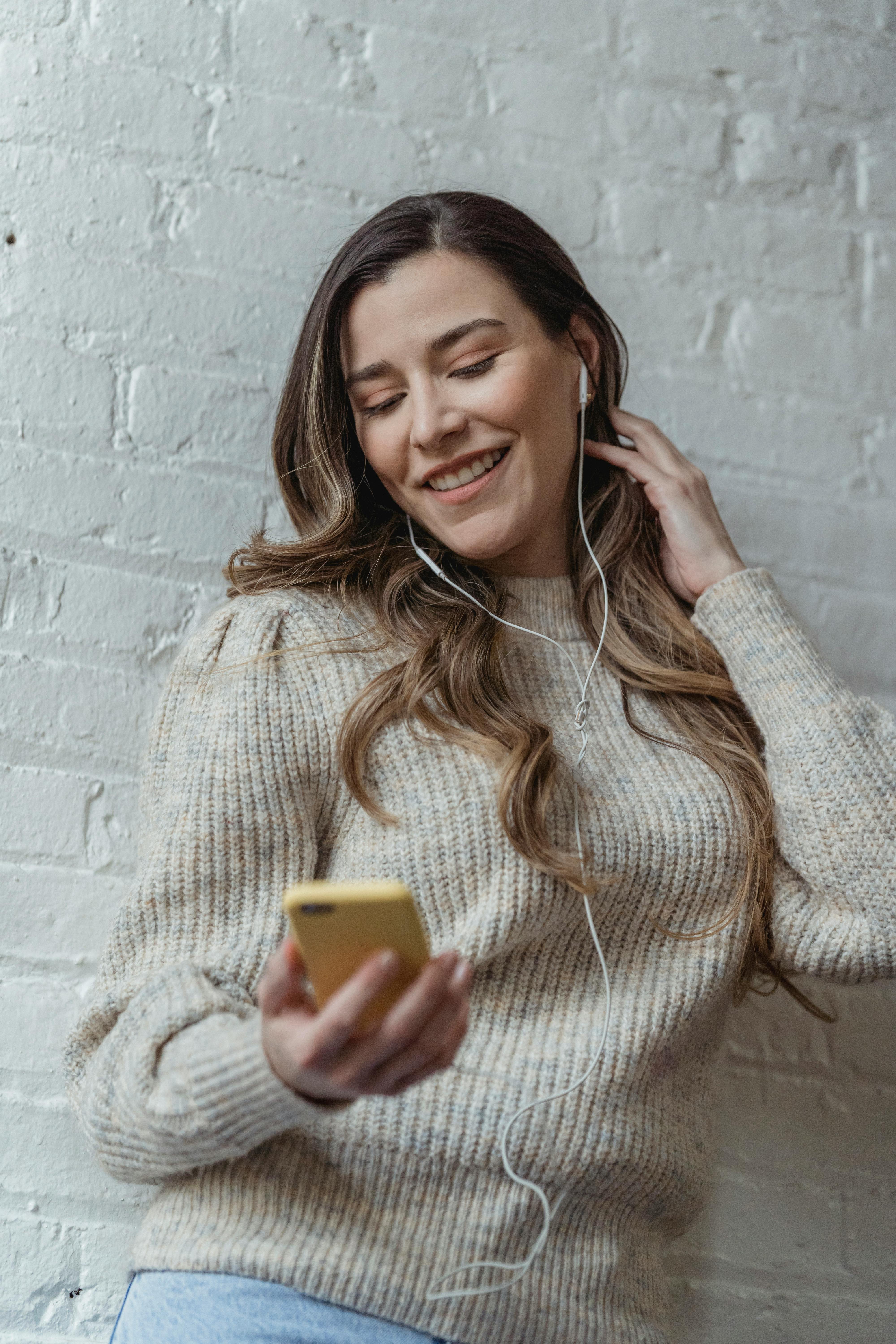 cheerful woman with earphones listening to music with smartphone