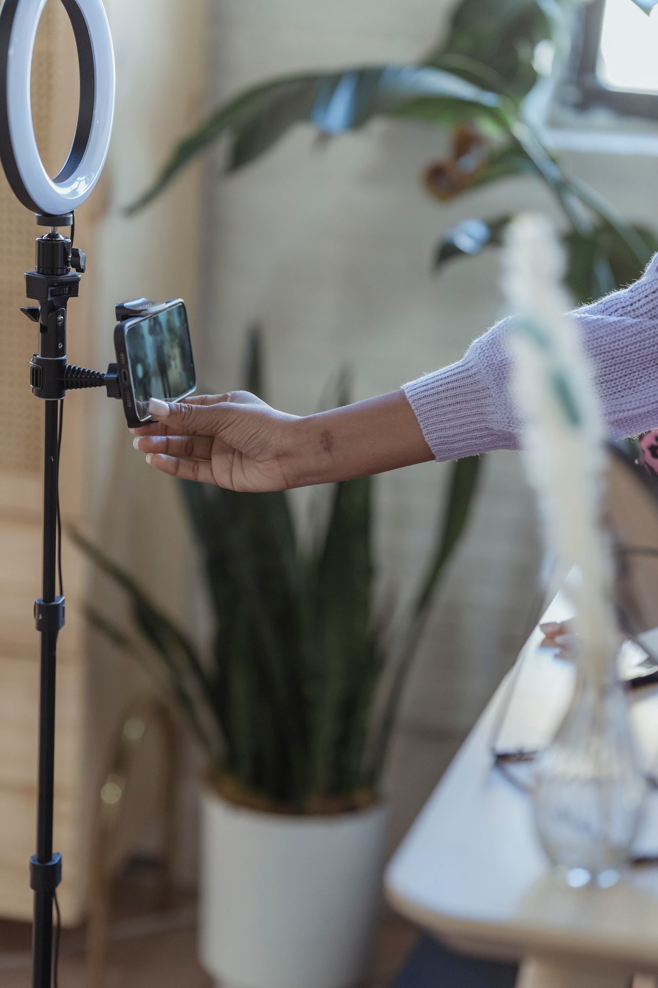 Creator adjusting a smartphone mounted on a ring light before filming
