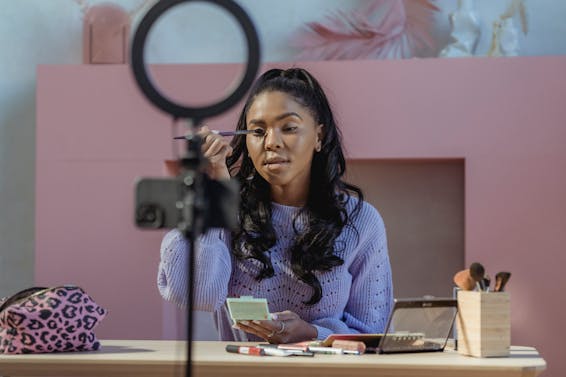 Black woman making makeup and filming vlog on smartphone