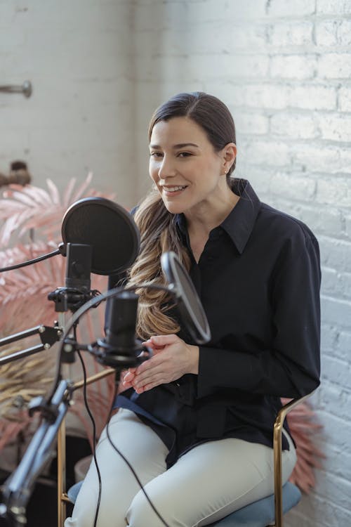 Smiling woman talking to microphone while recording podcast