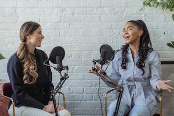 Smiling African American female guest gesticulating while having interview with journalist sitting near mic