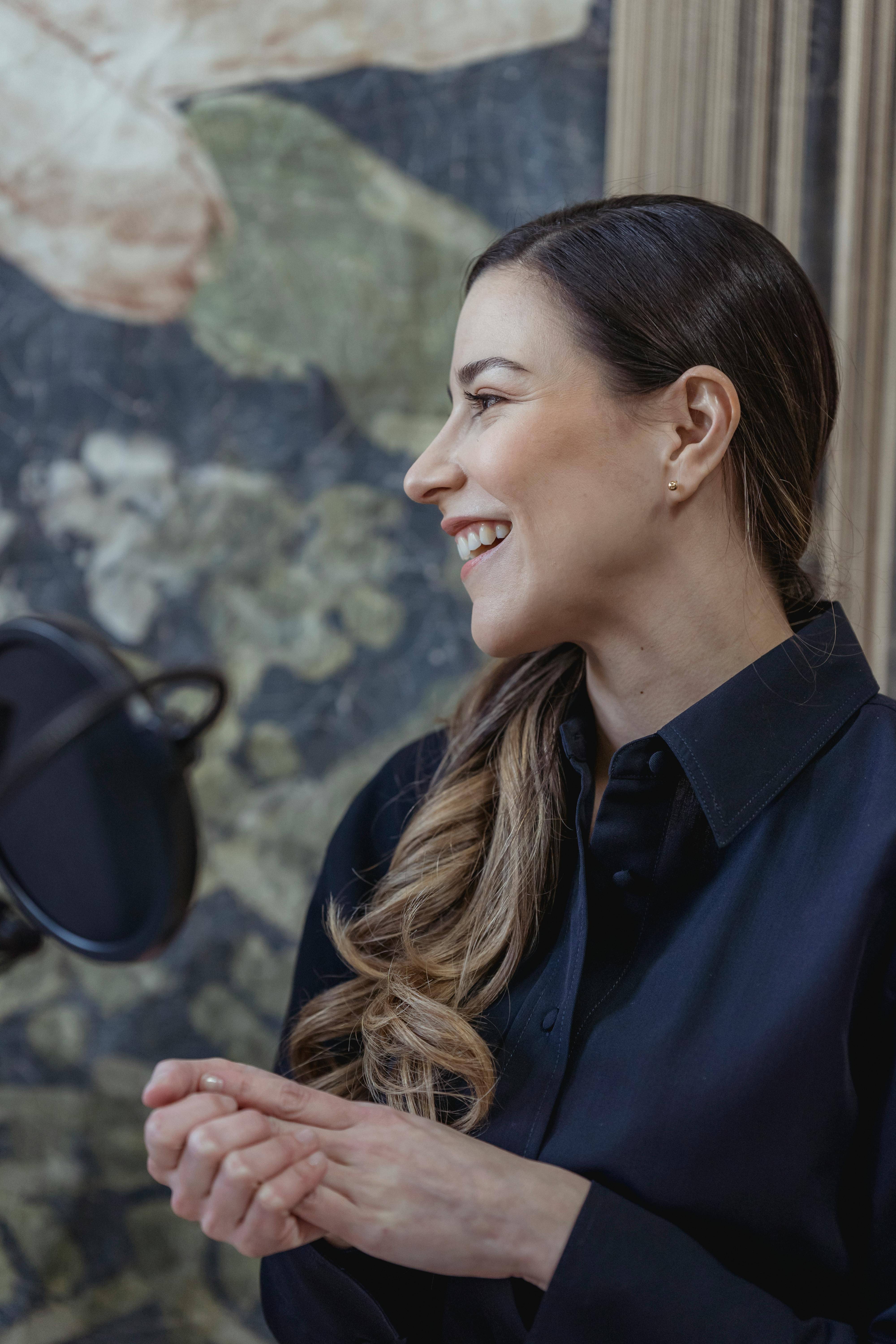 smiling woman recording podcast on mic