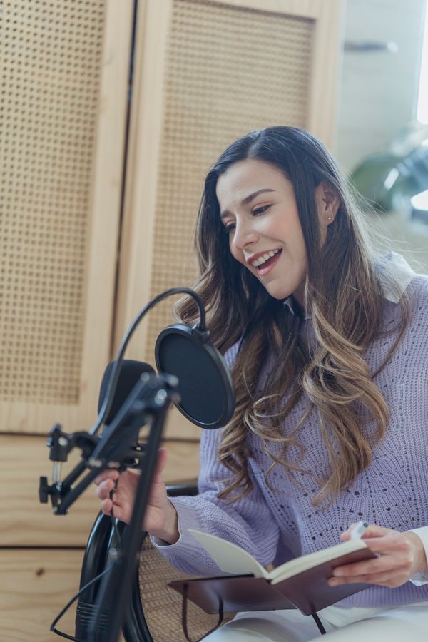 Guest with headphones reading notes into a studio microphone