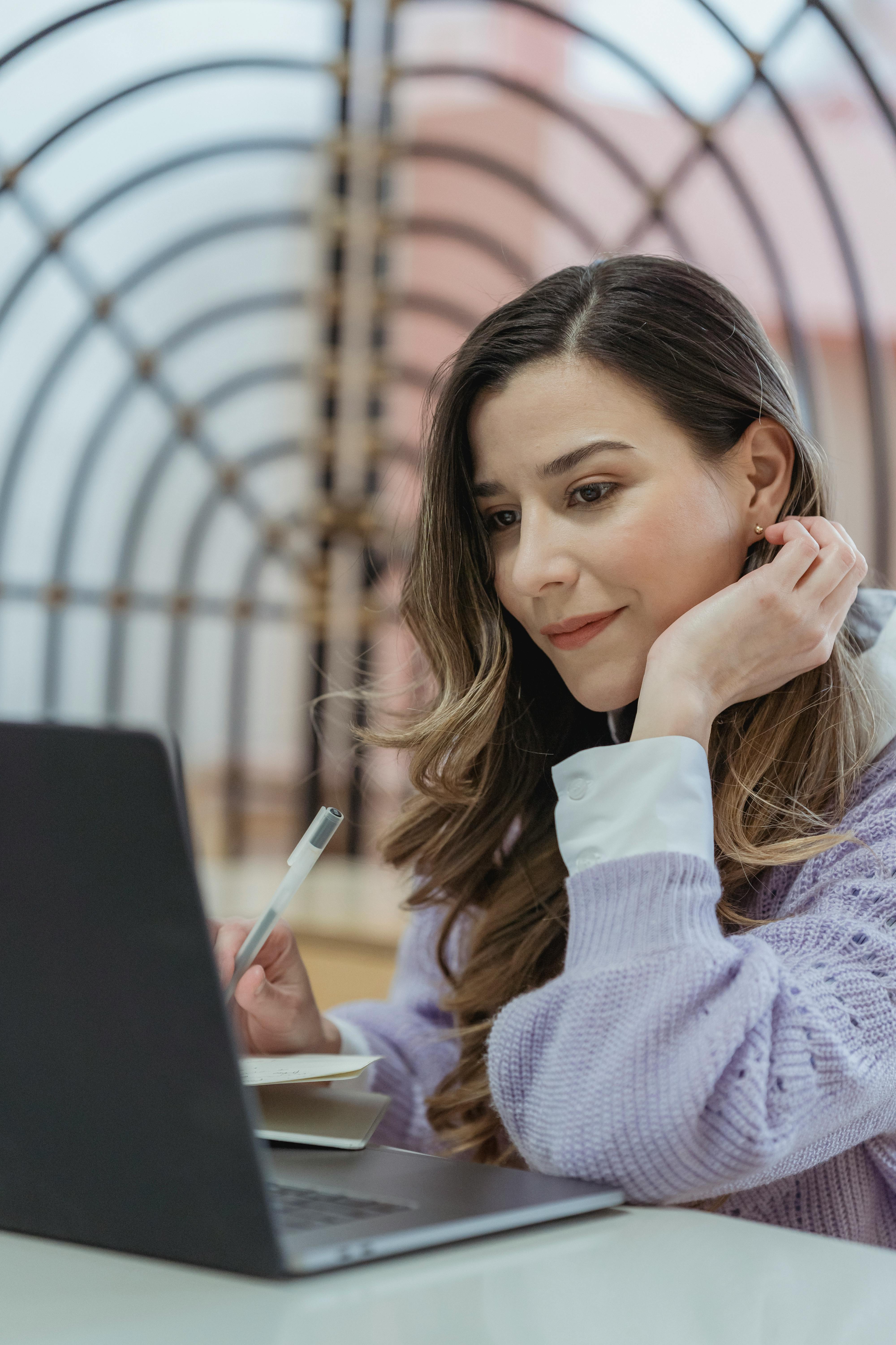 positive woman working on laptop and taking notes