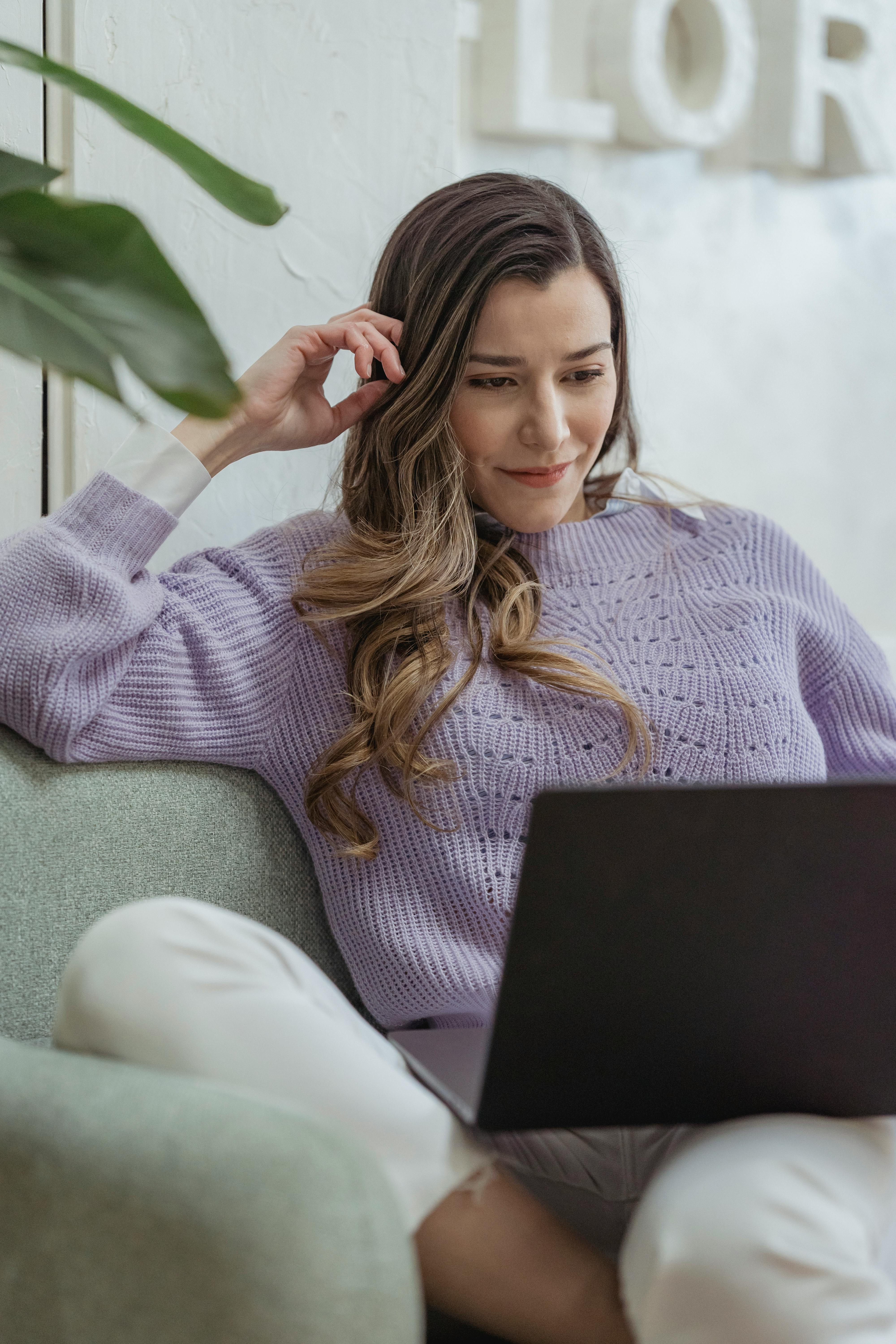 glad woman using laptop on couch