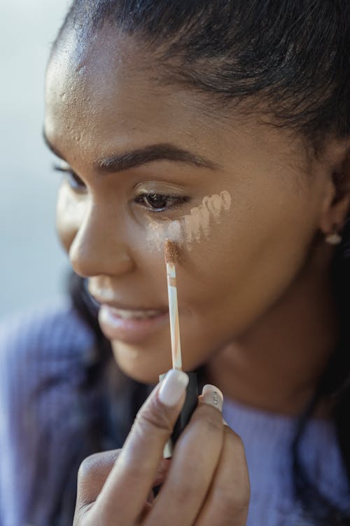 Free Crop black woman applying concealer on face Stock Photo