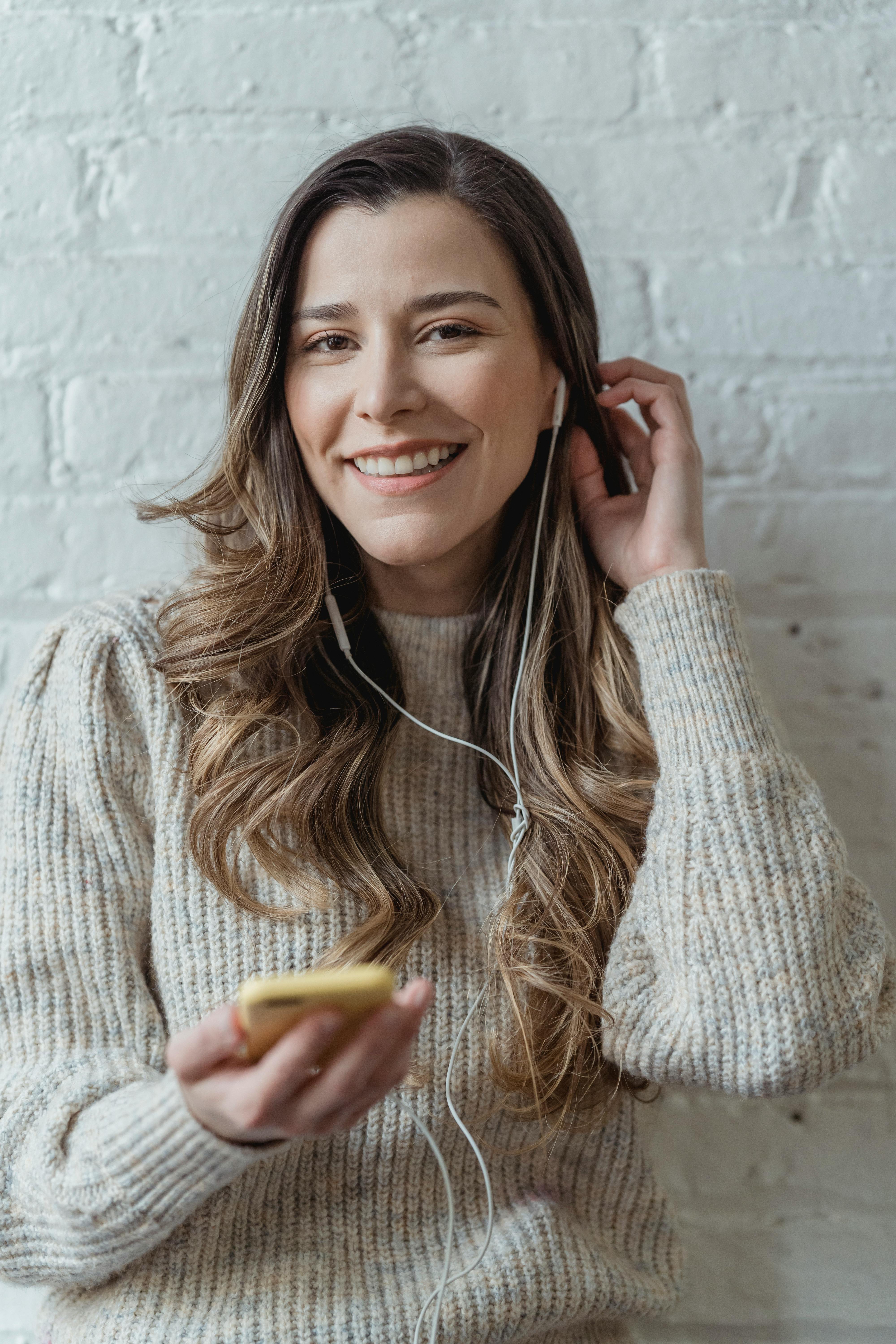 happy woman with smartphone listening to music in earphones