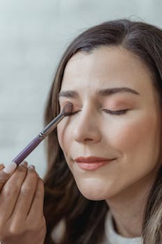 Close-up of a woman receiving eyeshadow makeup application in a studio.