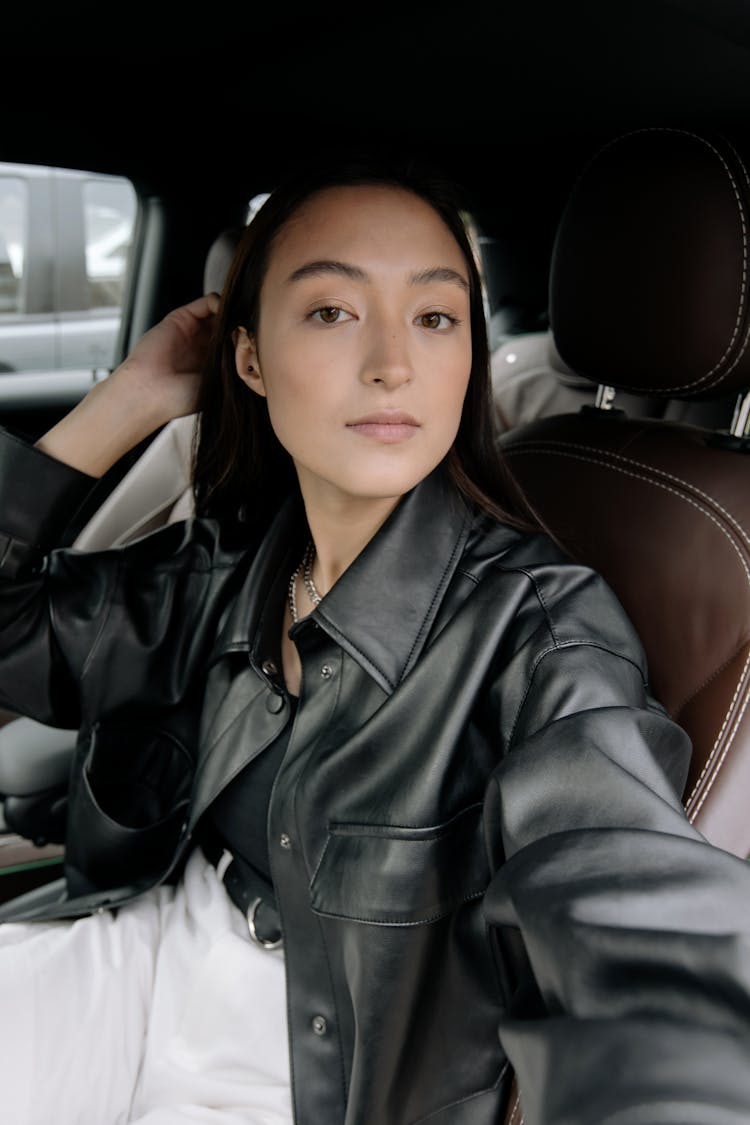 A Woman In Black Leather Jacket Sitting In The Car