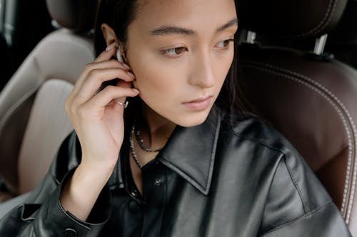 Woman in a Black Leather Jacket Touching Her Earpod