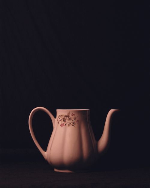 Free A beautifully crafted ceramic pitcher with floral design on a dark background, exuding vintage elegance. Stock Photo