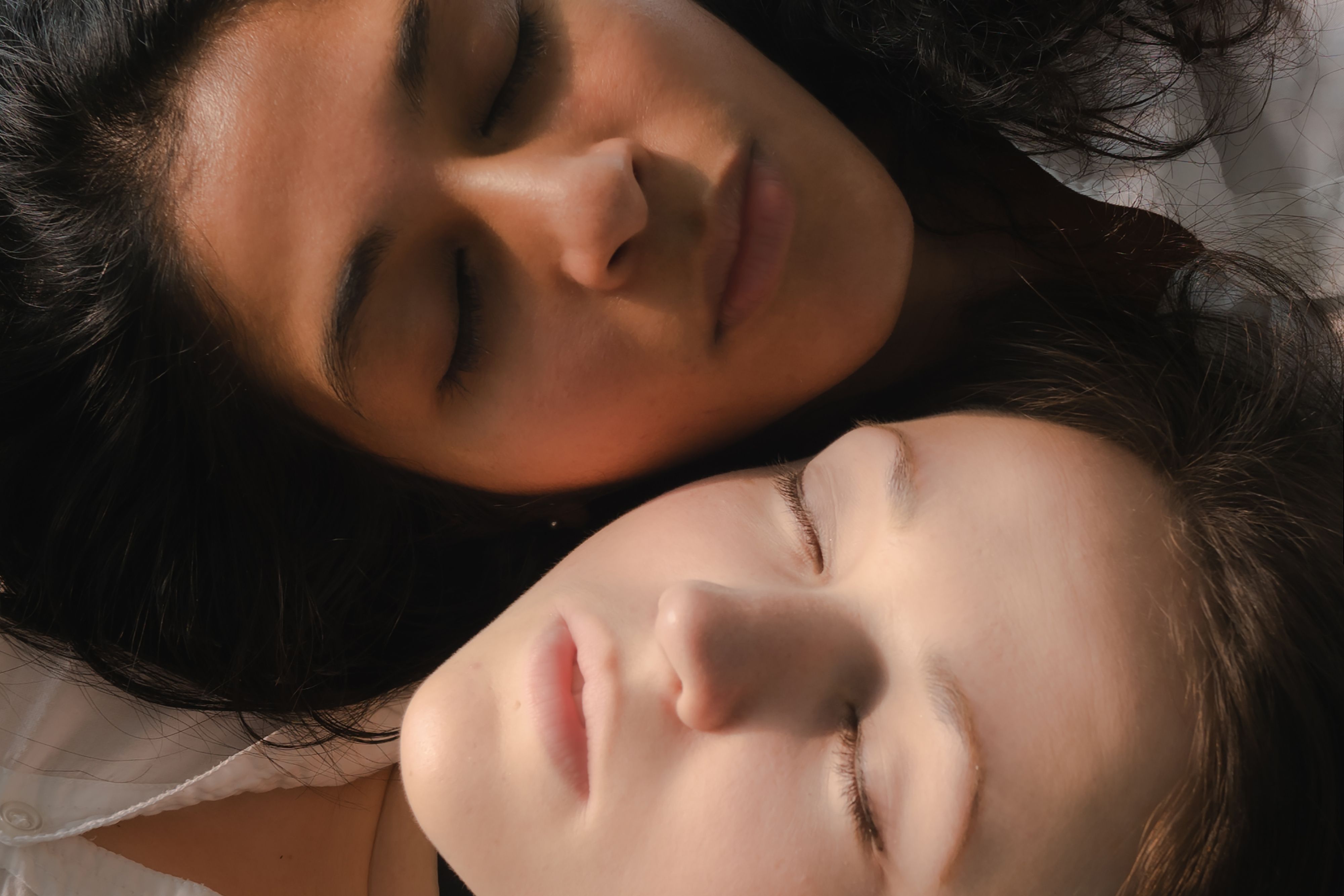 Close-up of two women sleeping peacefully together, showcasing intimacy and trust.