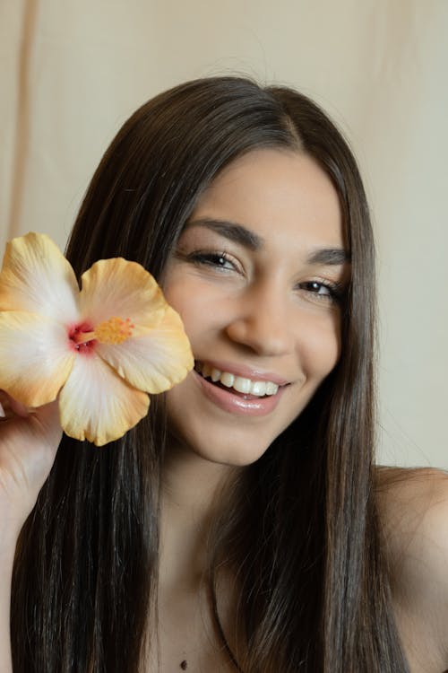 Close-Up Shot of a Pretty Woman Smiling while Holding a Flower