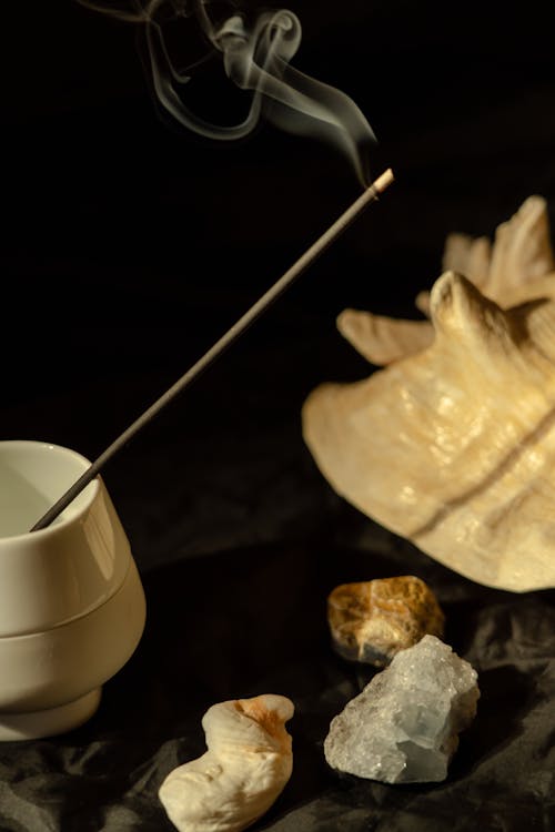 
A Close-Up Shot of a Lighted Incense beside Crystals