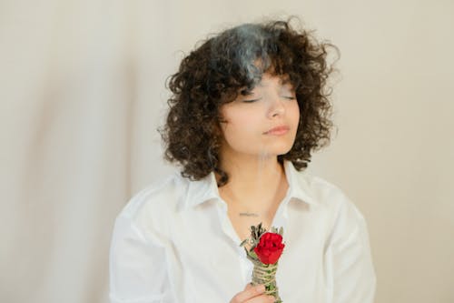 Free Photo of a Woman with Curly Hair Holding a Smudge Stick  Stock Photo