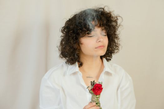 Photo of a Woman with Curly Hair Holding a Smudge Stick 