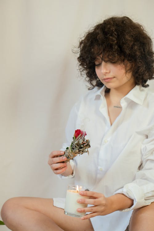 Free Photo of a Woman with Curly Hair Holding a Smudge Stick and a Candle Stock Photo