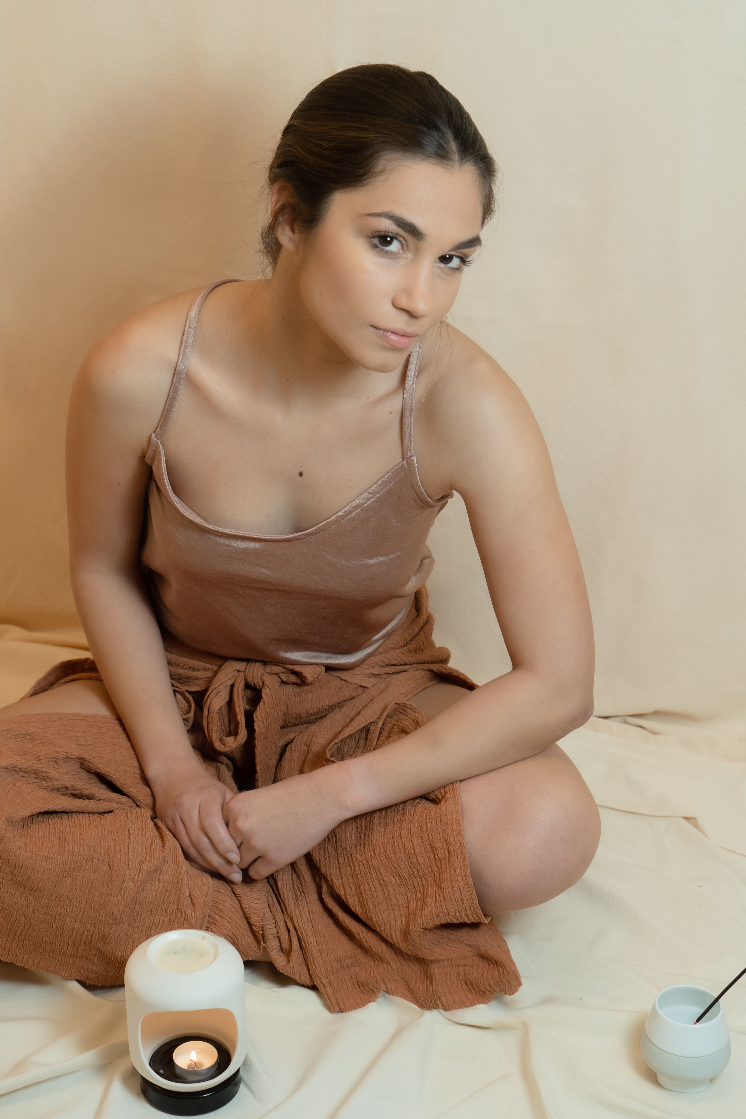 Serene portrait of a woman sitting indoors with warm candlelight, embodying tranquility and relaxation.