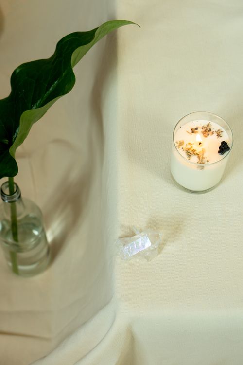 Free Lit candle next to green leaf and crystal on a table, creating a calming atmosphere. Stock Photo
