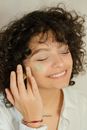 Photo of a Woman Applying Green Cream on Her Face