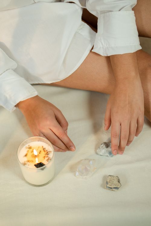 Free Close-up of hands near a candle and crystals on a white blanket, creating a peaceful ambiance. Stock Photo