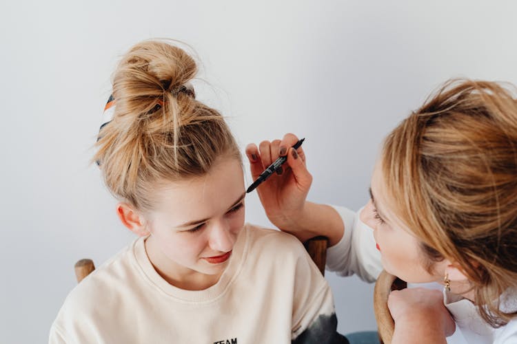 Photo Of A Mother Putting Makeup On Her Daughter