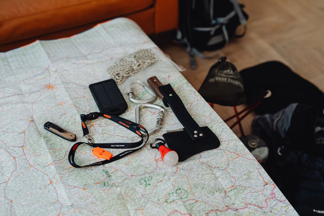 A set of basic hiking tools placed on an unfolded map, ready for navigation and survival.