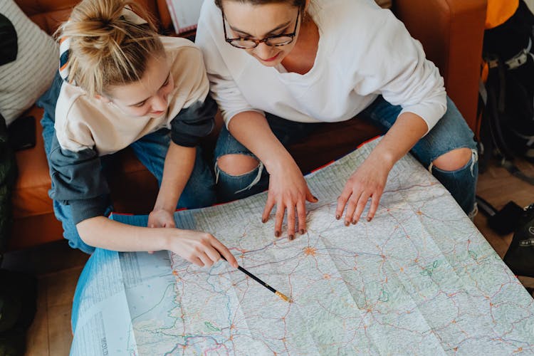 A Mother And Daughter Looking At A Map Planning Their Trip
