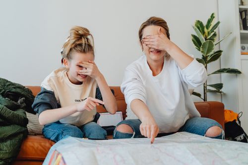 Free A mother and daughter planning a fun trip at home, pointing at a map Stock Photo