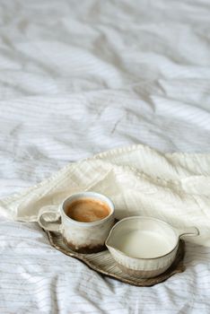 A comforting scene of coffee and milk on a textured bedspread tray.
