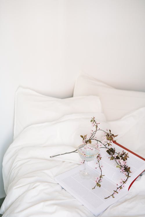 A Book and Flowers on a White Bed