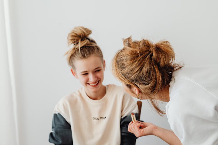 Women Having Fun While Putting Lipstick