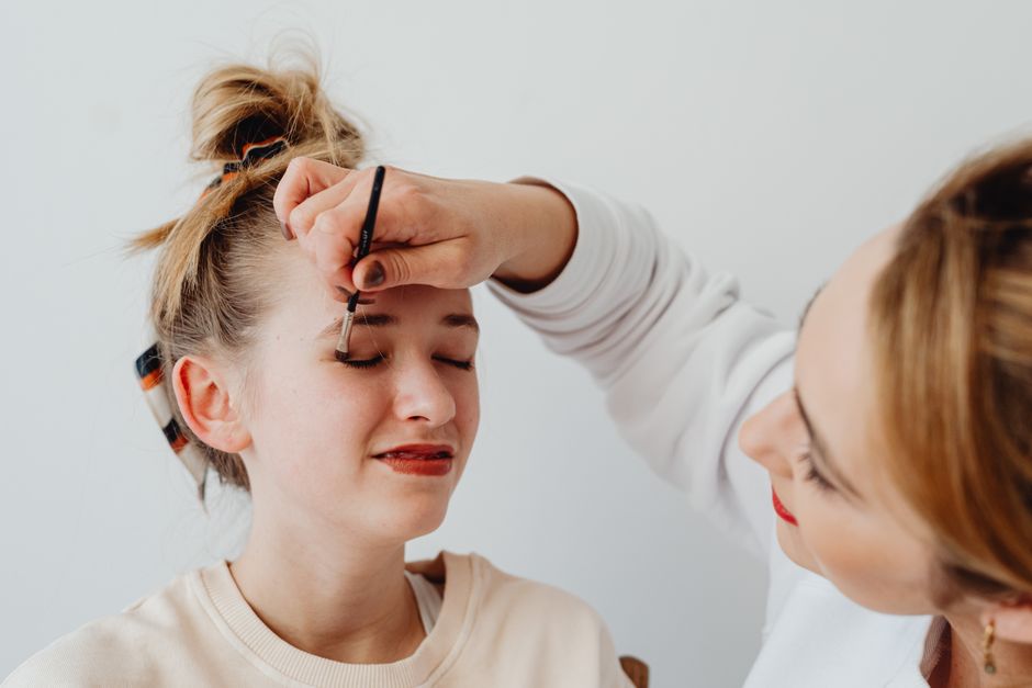 Two women engaged in a makeup application session with focus on eyeshadow.