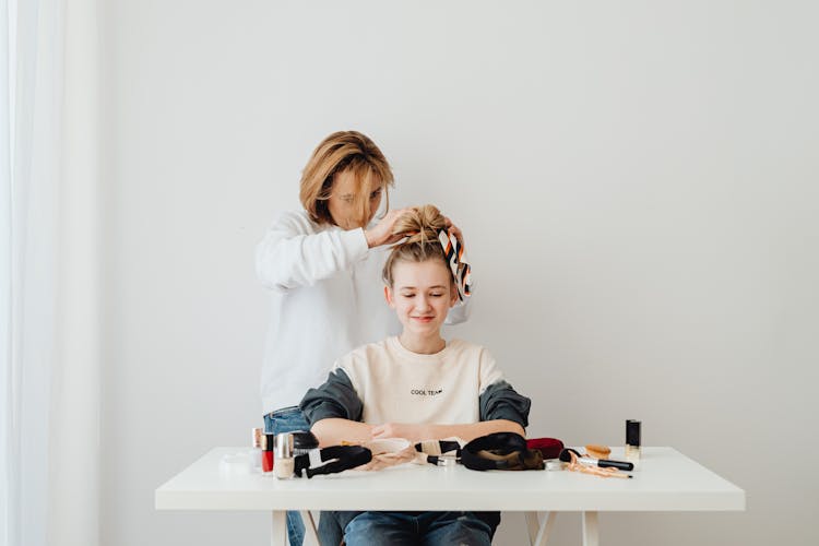 A Woman Tying Hair Of A Girl