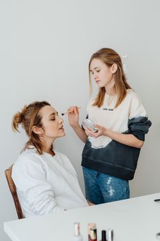 A young girl and her mother enjoying a fun makeup session indoors.