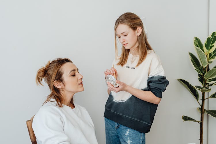 A Woman Putting Makeup On Another Woman