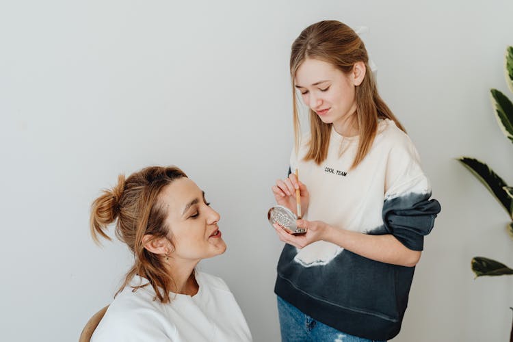 A Woman Putting Makeup On Another Woman