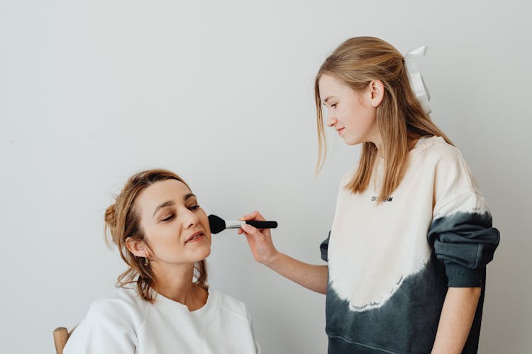 A Woman Putting Makeup On Another Woman