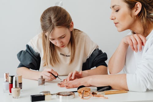 Free Blond Girl Painting Her Mothers Nails with Brown Nail Polish Stock Photo