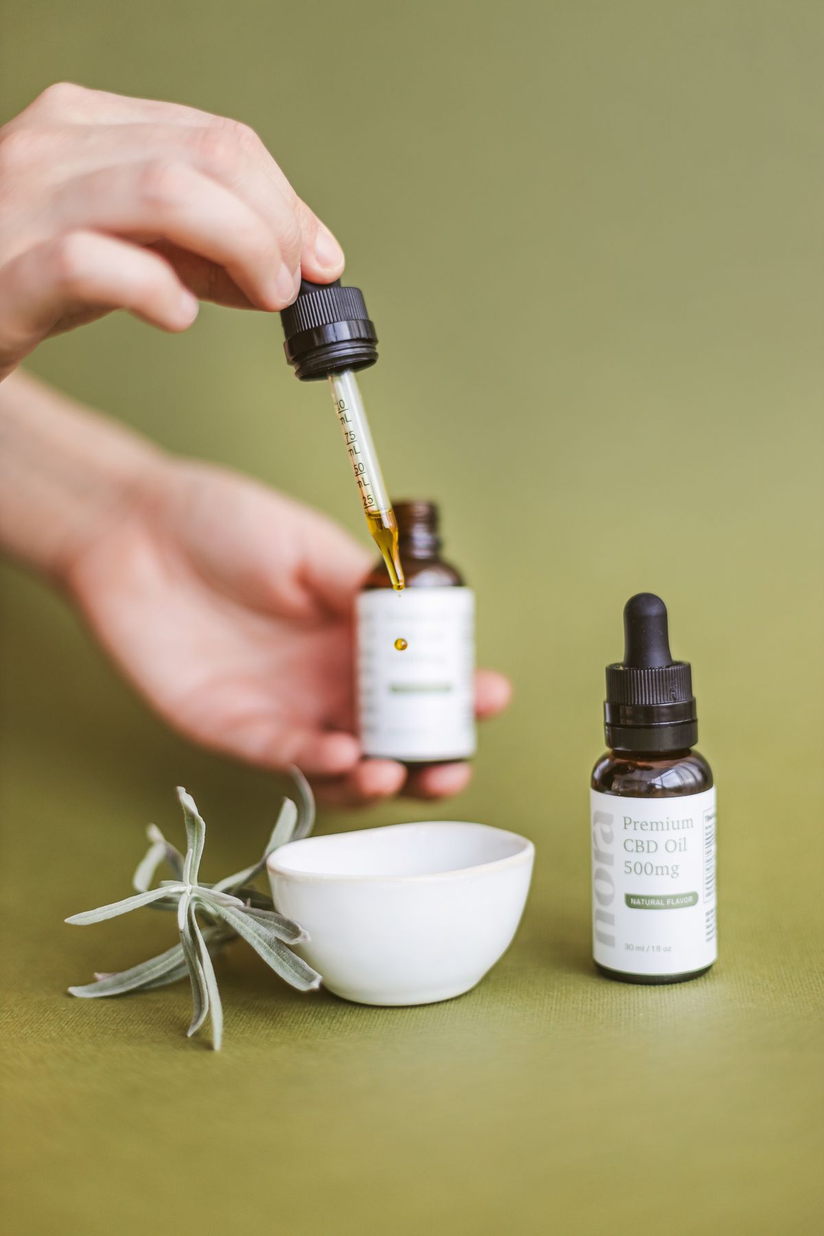 Hand using a dropper to dispense hemp extract, illustrating raw CBDa tinctures