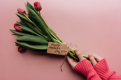 Free A hand holds a bouquet of tulips with a Happy Mother's Day tag on a pink background. Stock Photo